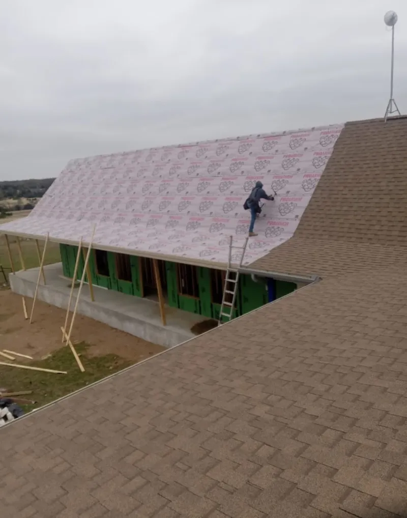 Worker preparing underlayment for a metal roof installation in Ardmore